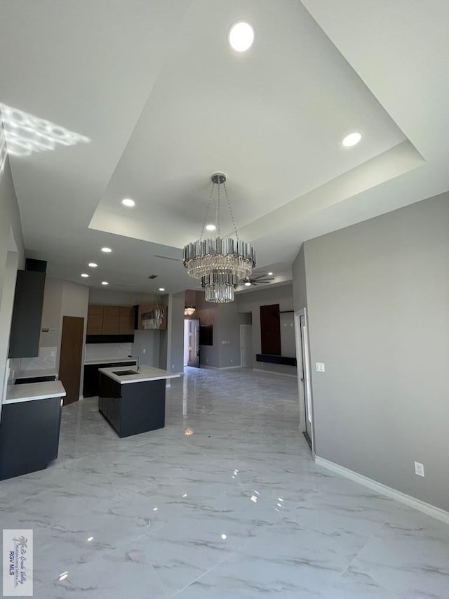 kitchen with a notable chandelier, open floor plan, baseboards, and a tray ceiling