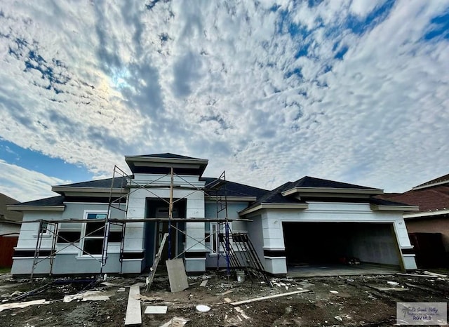 rear view of house featuring a garage and stucco siding