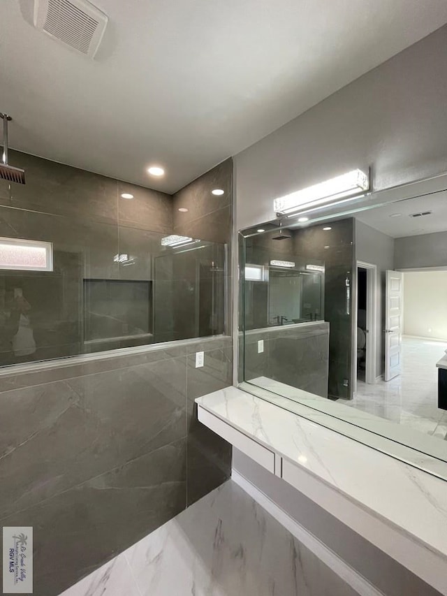 full bathroom with a tile shower, visible vents, and marble finish floor