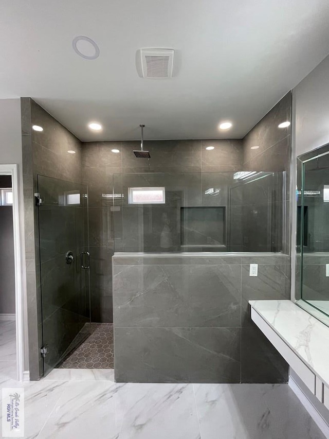 bathroom with a tile shower, visible vents, marble finish floor, and recessed lighting