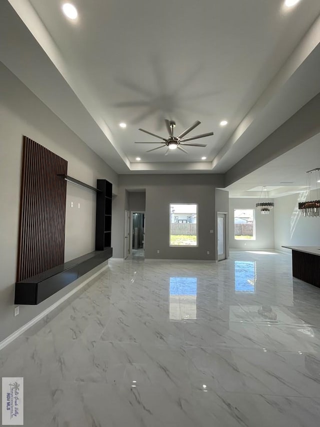 unfurnished living room featuring baseboards, a tray ceiling, recessed lighting, marble finish floor, and a ceiling fan