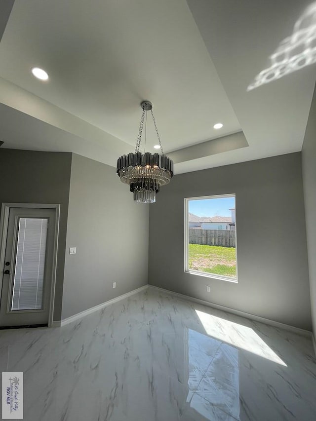 unfurnished room featuring baseboards, recessed lighting, a raised ceiling, a notable chandelier, and marble finish floor