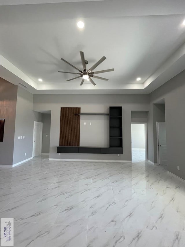 unfurnished living room featuring baseboards, a raised ceiling, and ceiling fan