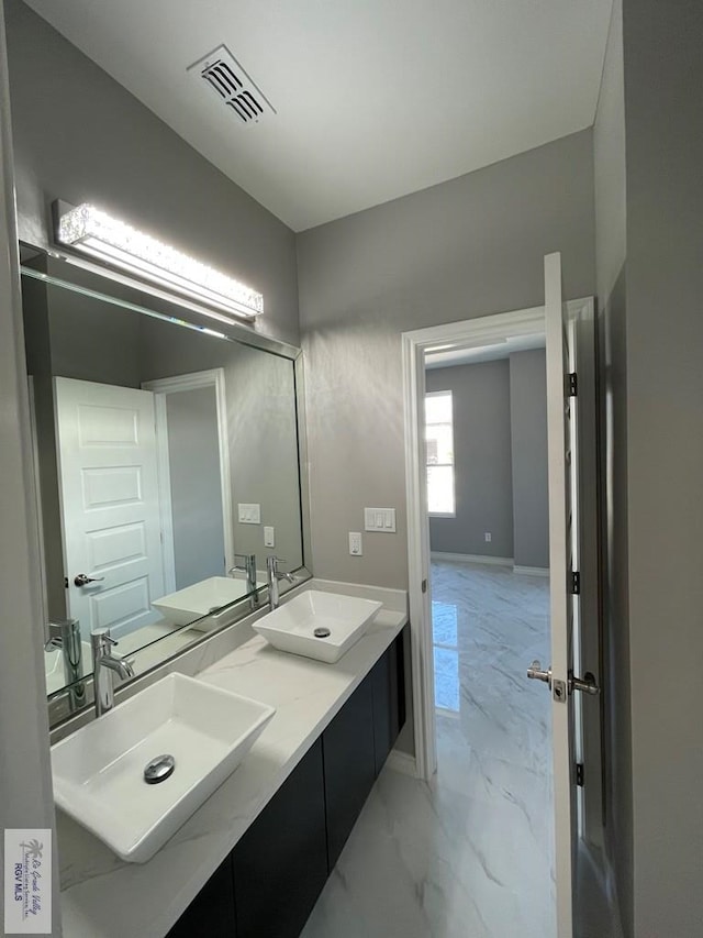 bathroom with a sink, visible vents, marble finish floor, and double vanity