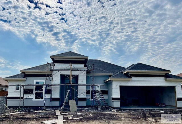 property under construction with an attached garage and roof with shingles