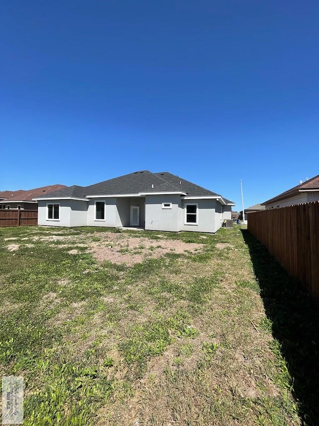 back of property with fence, a lawn, and stucco siding