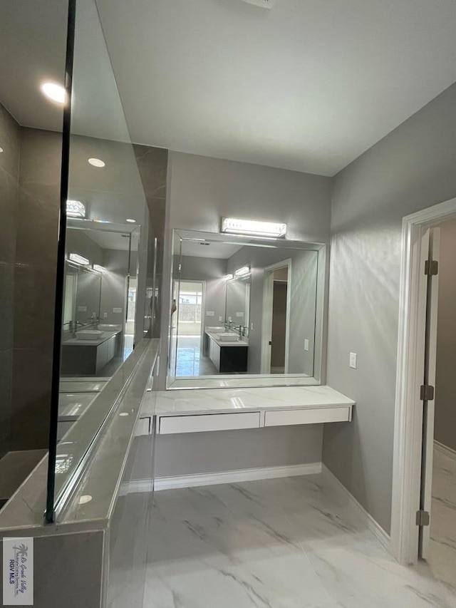 bathroom with baseboards, marble finish floor, and two vanities