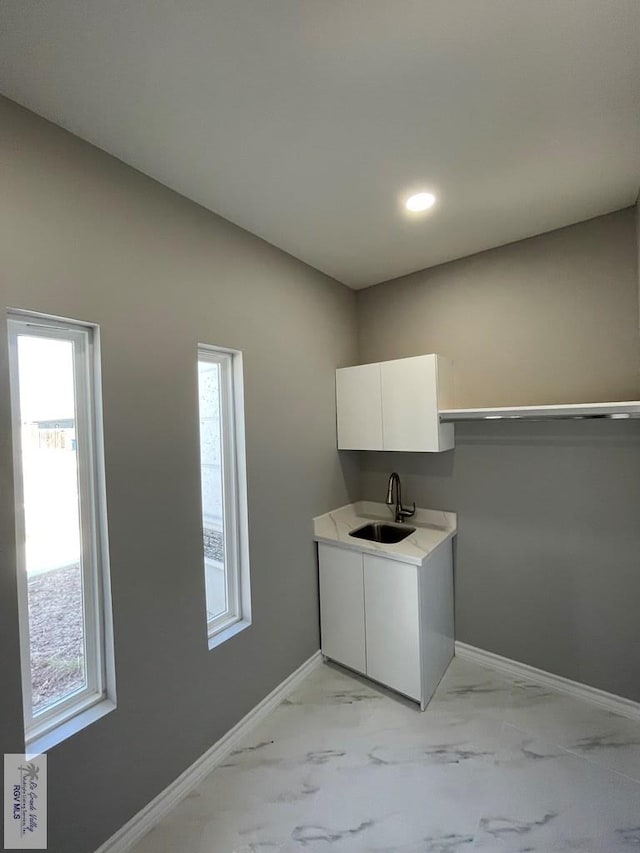 washroom featuring a wealth of natural light, baseboards, marble finish floor, and a sink