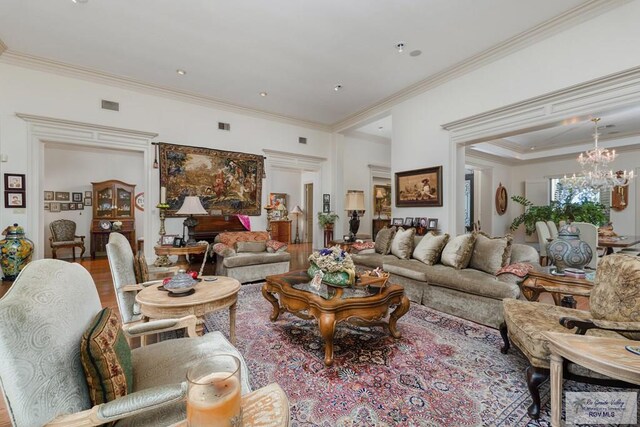 living room featuring hardwood / wood-style floors, crown molding, and an inviting chandelier