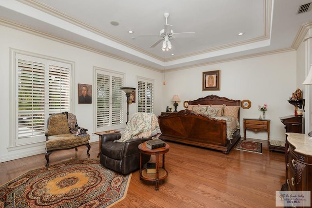 bedroom featuring ceiling fan, ornamental molding, a tray ceiling, and light hardwood / wood-style flooring