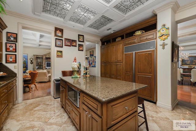 kitchen with built in appliances, a center island, light hardwood / wood-style floors, and crown molding