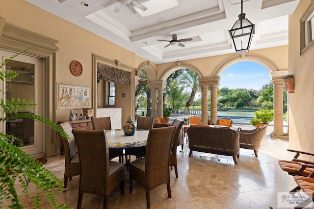 dining space featuring ceiling fan, ornate columns, and a tray ceiling