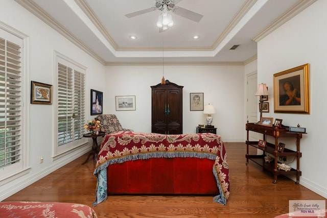 bedroom with hardwood / wood-style flooring, ceiling fan, ornamental molding, and a tray ceiling