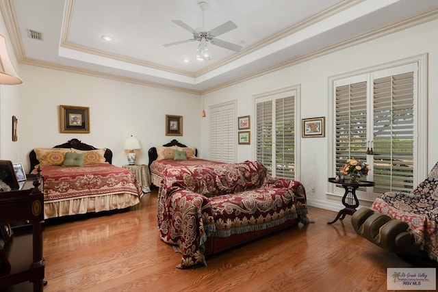 bedroom with a tray ceiling, ceiling fan, wood-type flooring, and ornamental molding