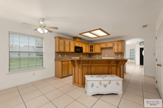 kitchen featuring tasteful backsplash, a center island, a kitchen bar, and light tile patterned floors