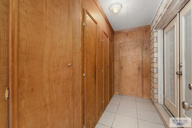 hallway with light tile patterned floors and wooden walls