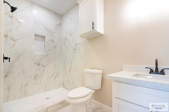 bathroom with tiled shower, vanity, and toilet