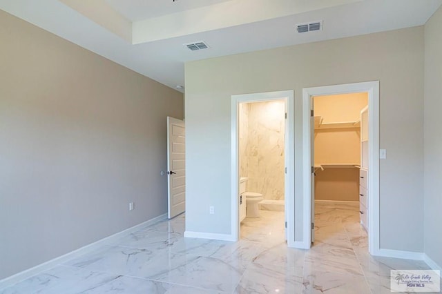 unfurnished bedroom featuring connected bathroom, a walk in closet, and a closet