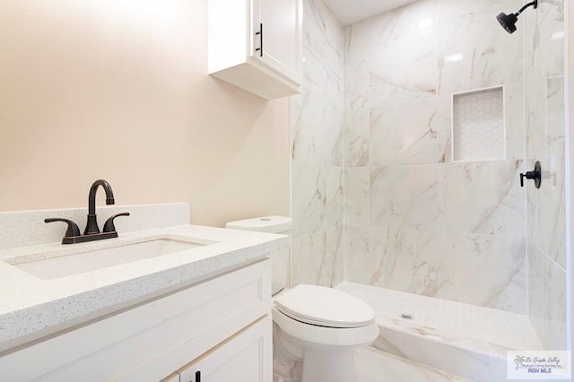 bathroom featuring tiled shower, vanity, and toilet