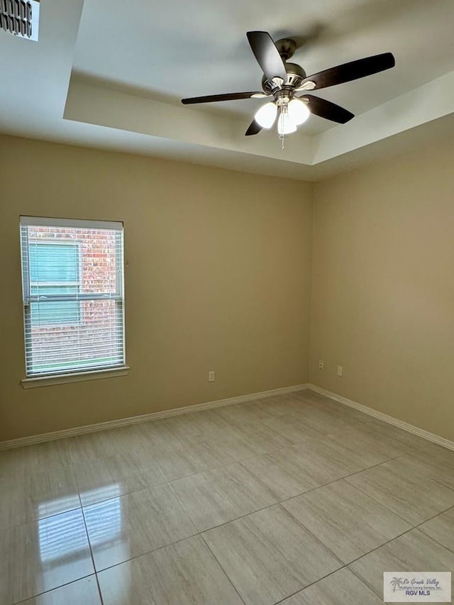 2611 E Eisenhower Ave Unit 50, Alton, TX 78573 - empty room with a tray ceiling, light tile patterned floors, a ceiling fan, and baseboards
