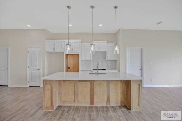 1829 Stirrup Cir, San Benito, TX 78586 - kitchen featuring a sink, a large island, light wood-style flooring, light countertops, and white cabinetry