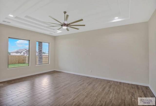 1829 Stirrup Cir, San Benito, TX 78586 - unfurnished room featuring wood finished floors, a tray ceiling, ceiling fan, baseboards, and recessed lighting