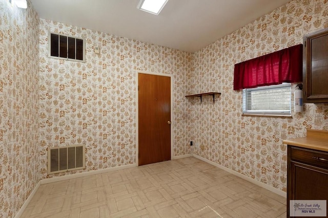 spare room with baseboards, visible vents, and wallpapered walls