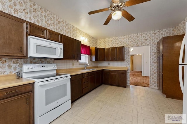 kitchen with wallpapered walls, white appliances, and a sink