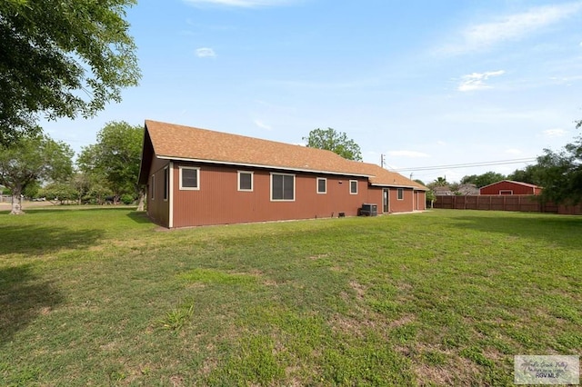 back of house with central air condition unit, a lawn, and fence
