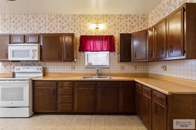 kitchen with wallpapered walls, light countertops, white appliances, and a sink