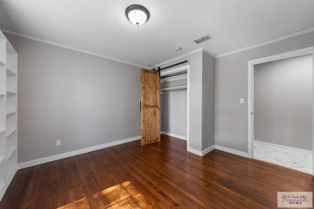 23570 Stuart Place Rd, Harlingen, TX 78552 - unfurnished bedroom with a closet, crown molding, baseboards, dark wood finished floors, and a barn door
