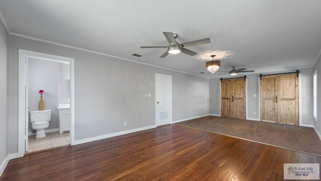 23570 Stuart Place Rd, Harlingen, TX 78552 - unfurnished bedroom with a barn door, wood finished floors, ornamental molding, and baseboards