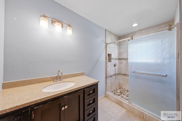 full bathroom with a shower stall, vanity, and tile patterned floors