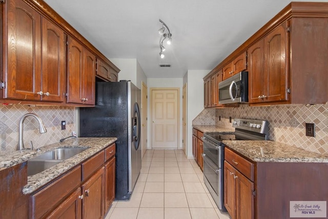 kitchen featuring stainless steel appliances, brown cabinetry, a sink, and visible vents