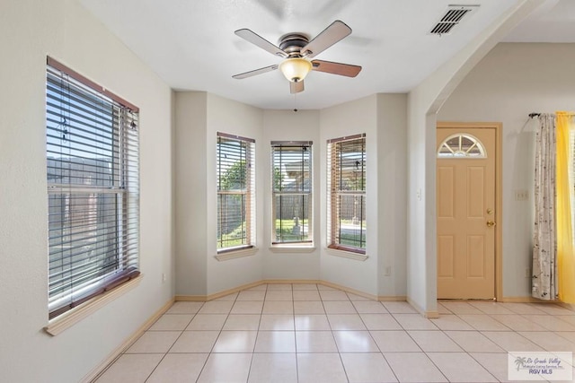 entryway featuring light tile patterned floors, visible vents, arched walkways, baseboards, and a ceiling fan