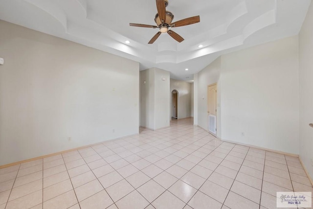 empty room featuring light tile patterned floors, arched walkways, a raised ceiling, ceiling fan, and recessed lighting