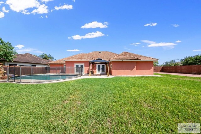 back of house featuring a gazebo, a fenced in pool, and a yard