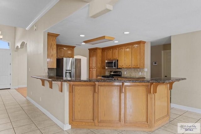 kitchen with light tile patterned flooring, kitchen peninsula, and appliances with stainless steel finishes