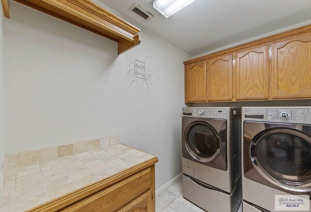 laundry room featuring cabinets, independent washer and dryer, and light tile patterned floors