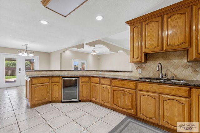 kitchen featuring sink, wine cooler, decorative backsplash, light tile patterned floors, and ceiling fan with notable chandelier