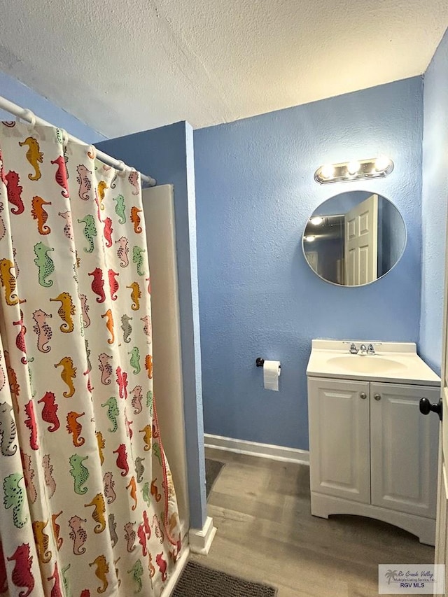 2013 E Jackson St, Harlingen, TX 78550 - full bath featuring wood finished floors, baseboards, a textured ceiling, a shower with curtain, and vanity