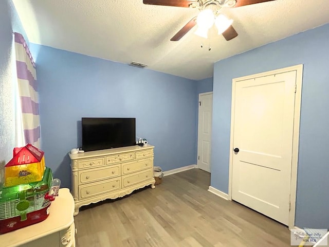 2013 E Jackson St, Harlingen, TX 78550 - bedroom featuring light wood finished floors, a ceiling fan, baseboards, and a textured ceiling