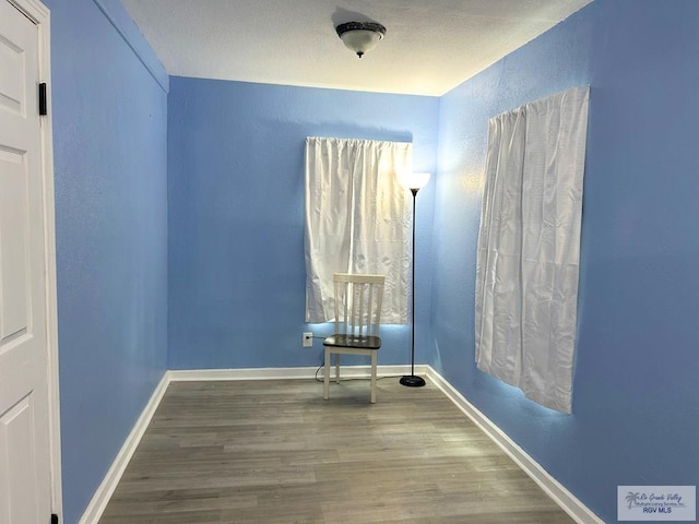 2013 E Jackson St, Harlingen, TX 78550 - empty room with wood finished floors, a textured wall, and baseboards