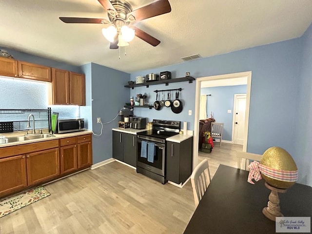 2013 E Jackson St, Harlingen, TX 78550 - kitchen with stainless steel appliances, a sink, brown cabinets, light countertops, and light wood-type flooring