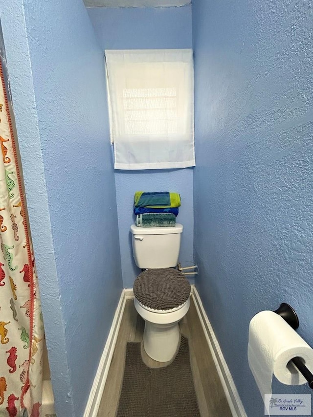 2013 E Jackson St, Harlingen, TX 78550 - bathroom with toilet, a shower with curtain, and baseboards