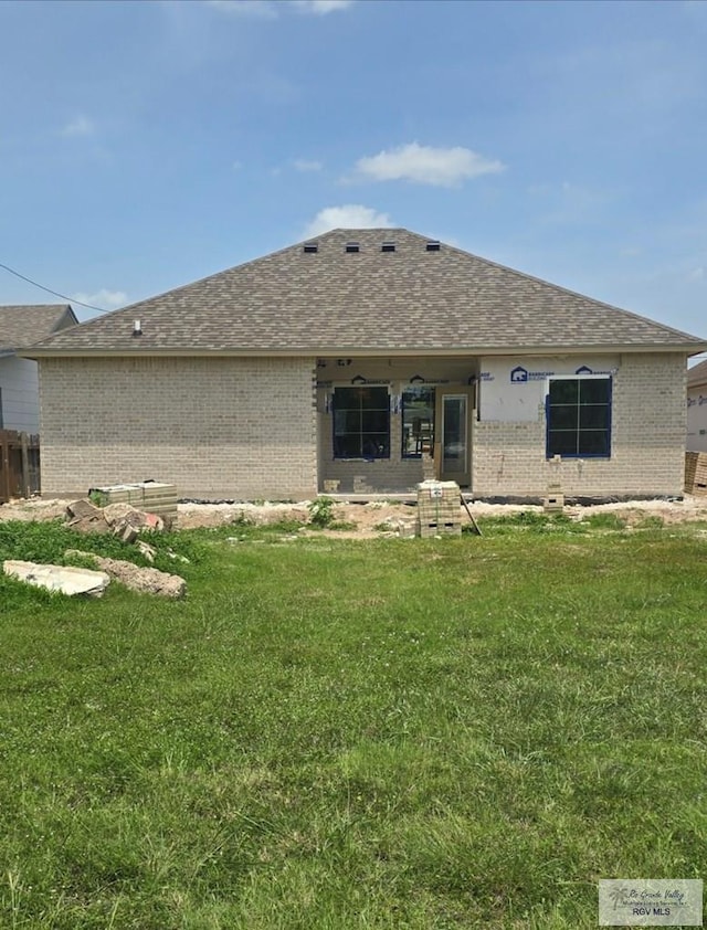 back of property featuring brick siding, a lawn, and a shingled roof