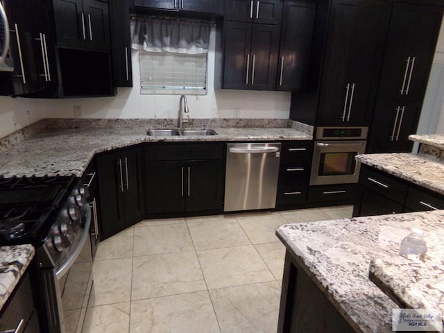 kitchen with light stone countertops, light tile patterned floors, stainless steel appliances, and sink