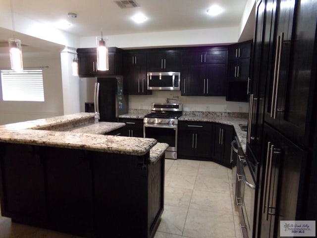 kitchen featuring light stone countertops, pendant lighting, a kitchen island, and stainless steel appliances