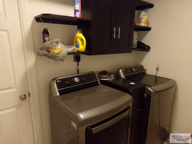 clothes washing area featuring cabinets and independent washer and dryer