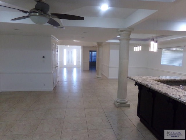 interior space with decorative light fixtures, ceiling fan, light stone countertops, and decorative columns